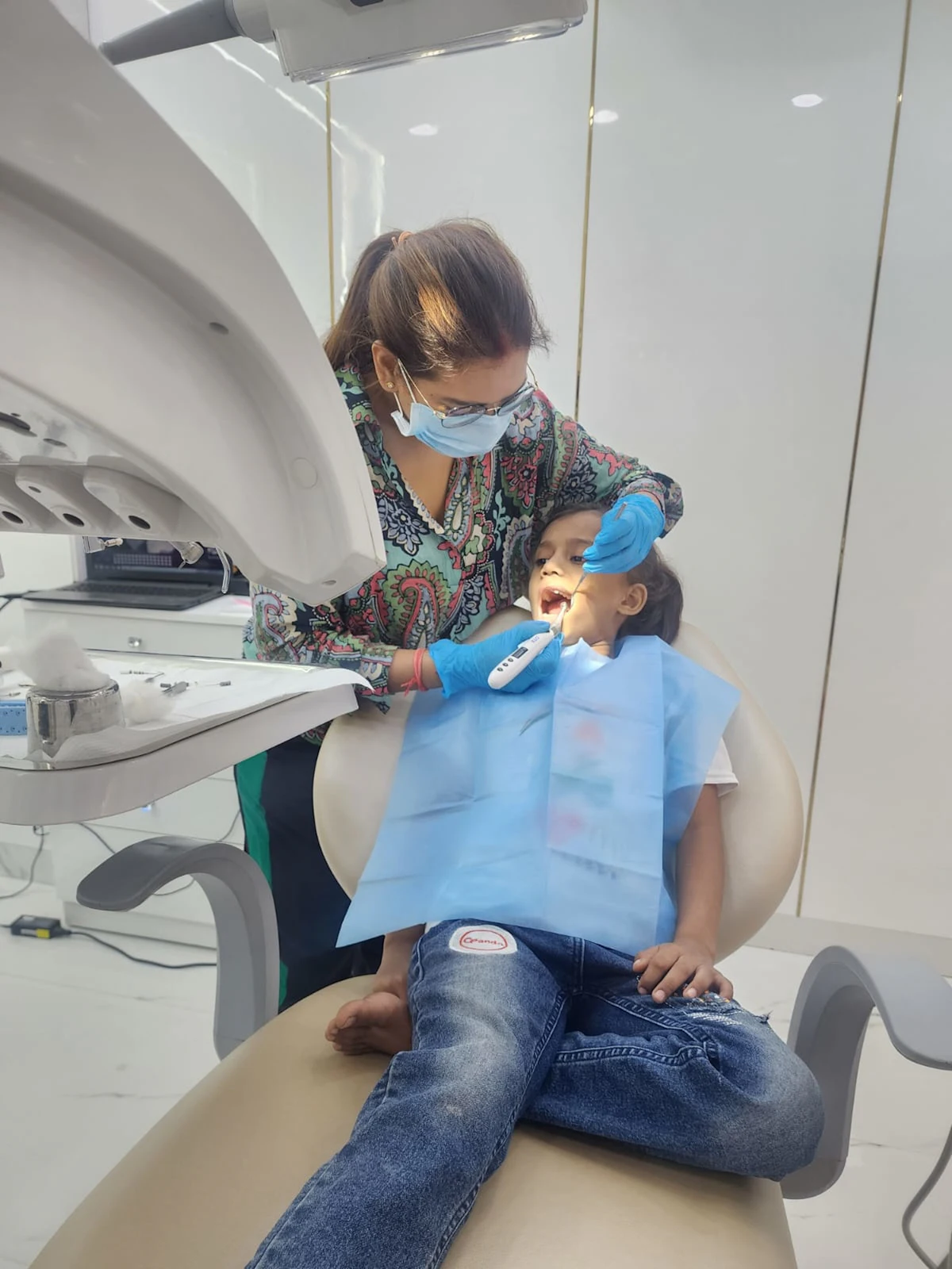 A dentist gently checking a young boy's teeth